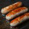 10 fat sausages sizzling in a pan