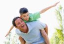 Man giving young boy piggyback ride outdoors.