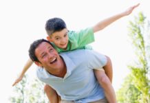 Man giving young boy piggyback ride outdoors.