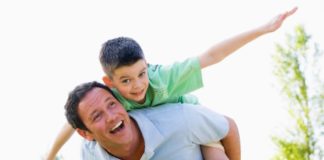 Man giving young boy piggyback ride outdoors.