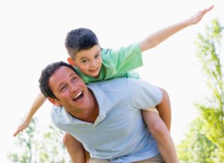 Man giving young boy piggyback ride outdoors.