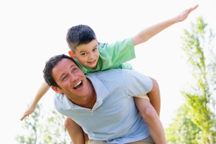 Man giving young boy piggyback ride outdoors.