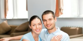 A smiling couple sit in a conservative pose.