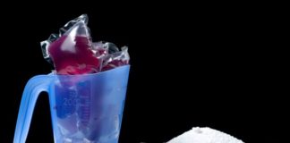 Various kinds of laundry detergent on a white counter with a black backdrop.