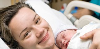 A happy mother in a hospital bed with newborn baby.