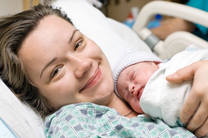 A happy mother in a hospital bed with newborn baby.