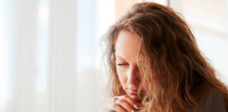 Sad beautiful woman against window.