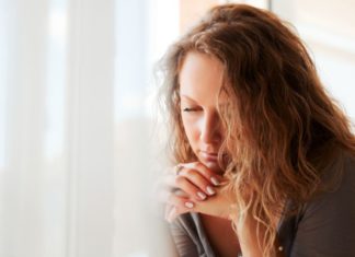 Sad beautiful woman against window.