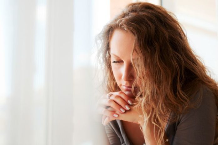 Sad beautiful woman against window.