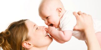 A mother lifts her baby above her head.