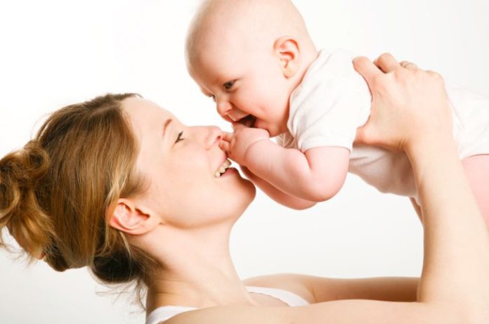 A mother lifts her baby above her head.