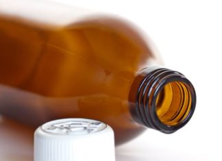 A brown medicine bottle on its side with the white cap in front.