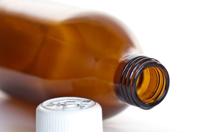 A brown medicine bottle on its side with the white cap in front.