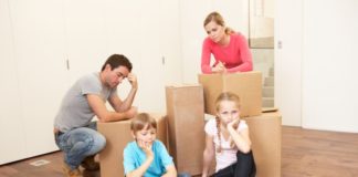 Staged image with family and boxes. Nobody looks happy.