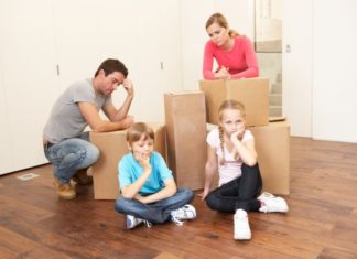 Staged image with family and boxes. Nobody looks happy.