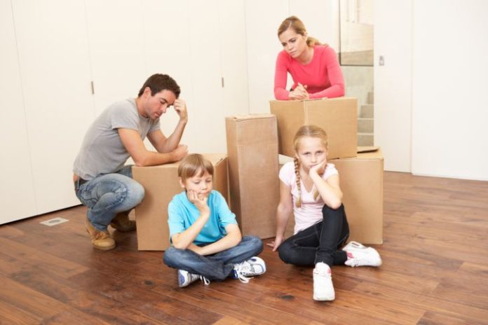 Staged image with family and boxes. Nobody looks happy.