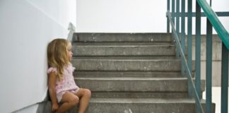 Upset little girl sits in stairwell.