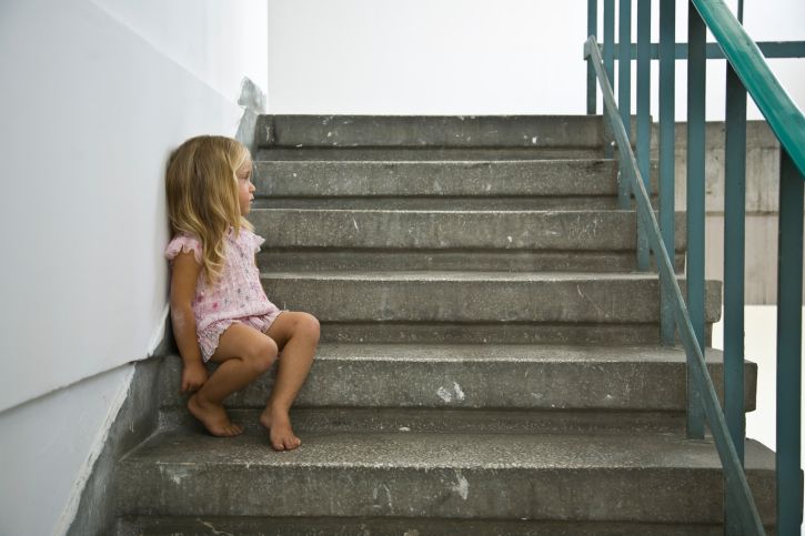 Upset little girl sits in stairwell.
