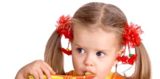 Girl with long pigtails brushing teeth.