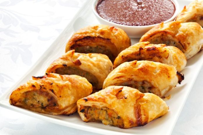 Sausage rolls on a tray with dipping sauce.