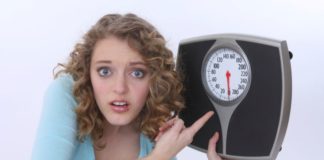 Girl holds a scale and points to it.