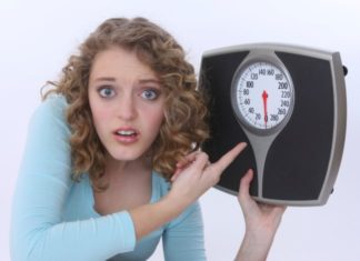 Girl holds a scale and points to it.