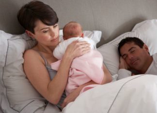 Man sleeps while unhappy looking mother holds baby.