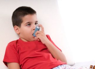 Boy in bed takes his inhaler.