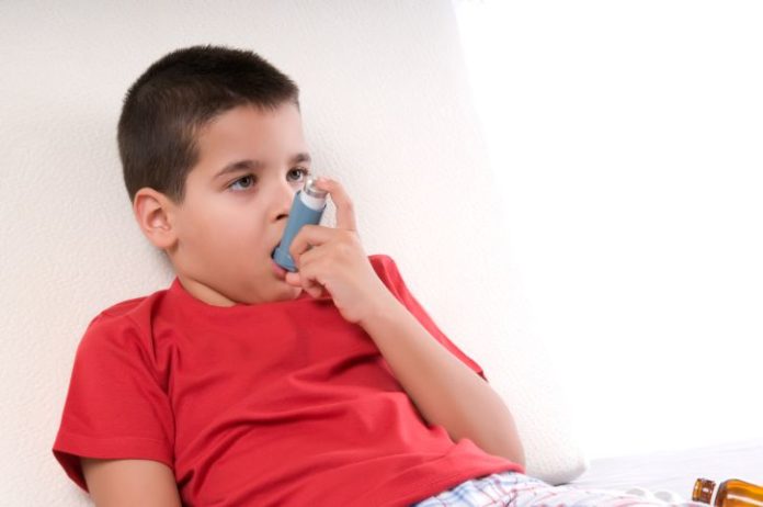 Boy in bed takes his inhaler.