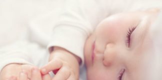 Close-up portrait of a beautiful sleeping baby in white.