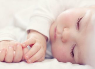 Close-up portrait of a beautiful sleeping baby in white.