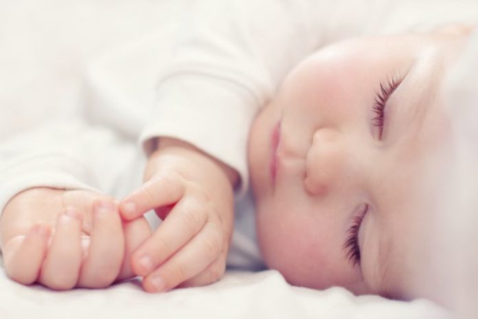 Close-up portrait of a beautiful sleeping baby in white.