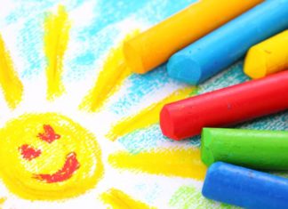 Crayons and a drawing of a smiling sun.