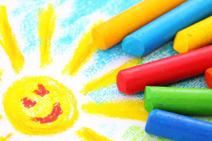 Crayons and a drawing of a smiling sun.