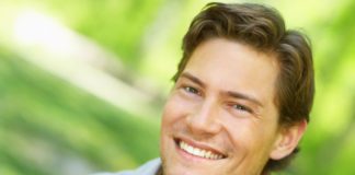 A man with a side parted hair style smiles to camera.