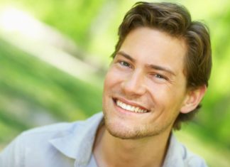 A man with a side parted hair style smiles to camera.