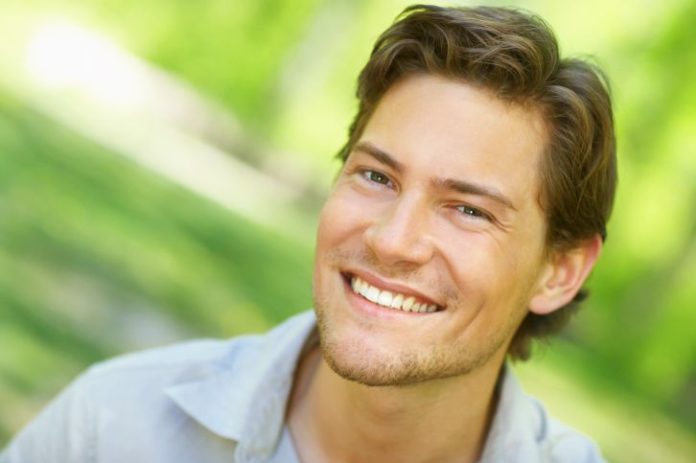 A man with a side parted hair style smiles to camera.