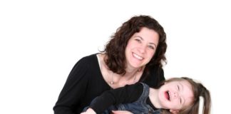 A mother and daughter, both in denim and black, smile.