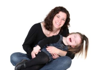 A mother and daughter, both in denim and black, smile.