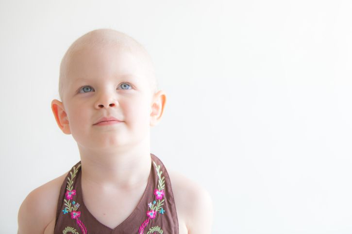 A bald little girl looking angelic.