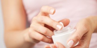 Woman holds a small jar of lotion.