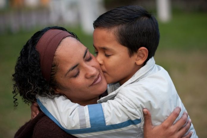 Young boy kisses his mother on the cheek.