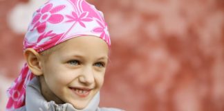 A pale little girl wearing a winter goat with a pink scarf over her head.