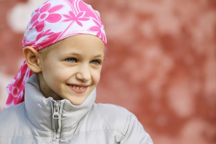 A pale little girl wearing a winter goat with a pink scarf over her head.