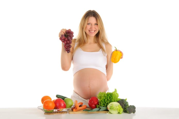 Happy pregnant woman with fruits and vegetables