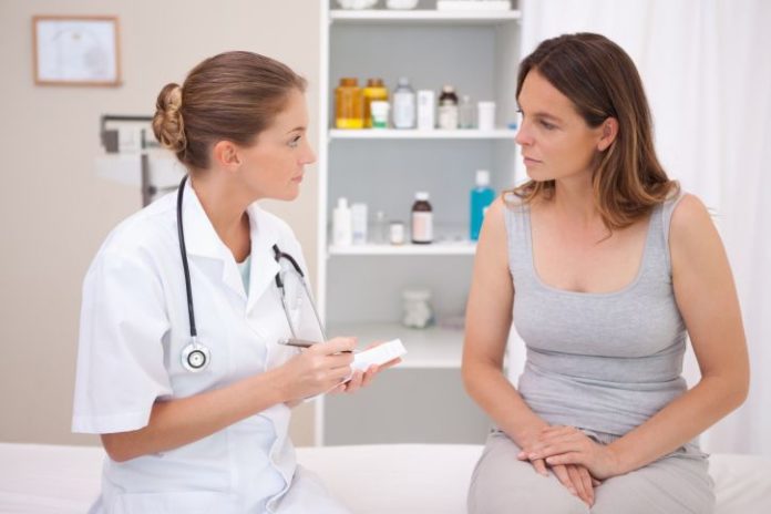 Woman talks with female doctor. Doctor takes notes.