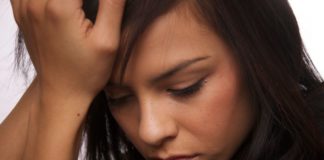 Depressed teen girl holds her head in her hands.