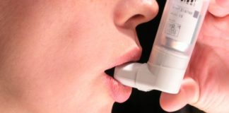 A close up shot of a woman taking an inhaler.