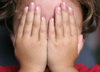 Child hiding face with hands
