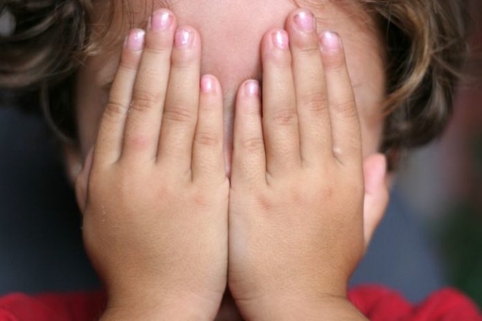 Child hiding face with hands